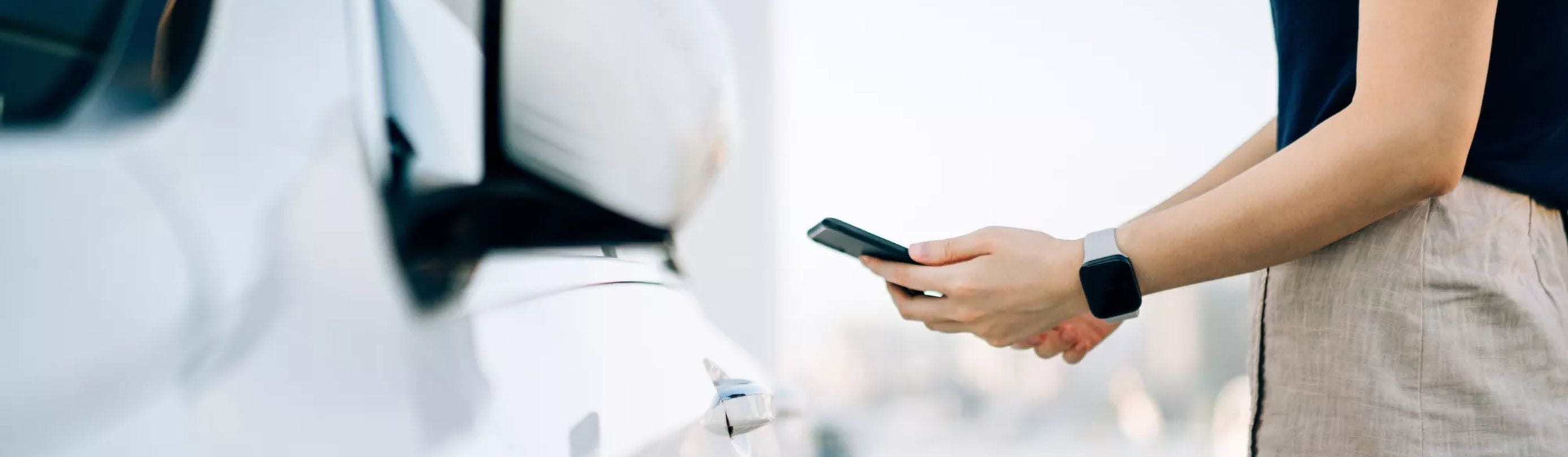 Woman with smartphone next to car